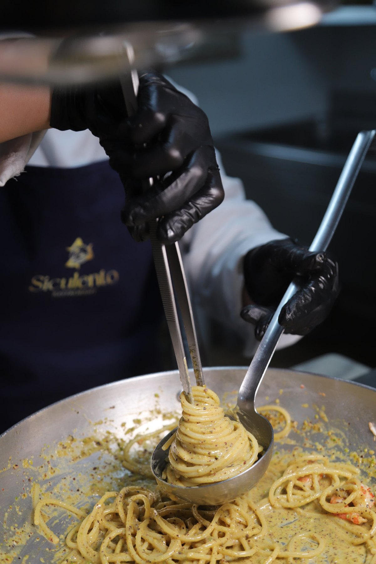 Le mani della chef mentre arrotola la pasta al pistacchio in padella
